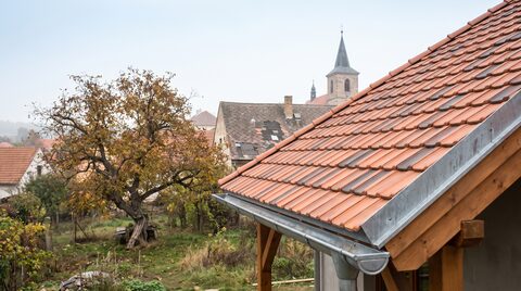 Ilustrační foto: hotová sedlová střecha vesnického domu s novou pálenou krytinou a titanzinkovým okapem